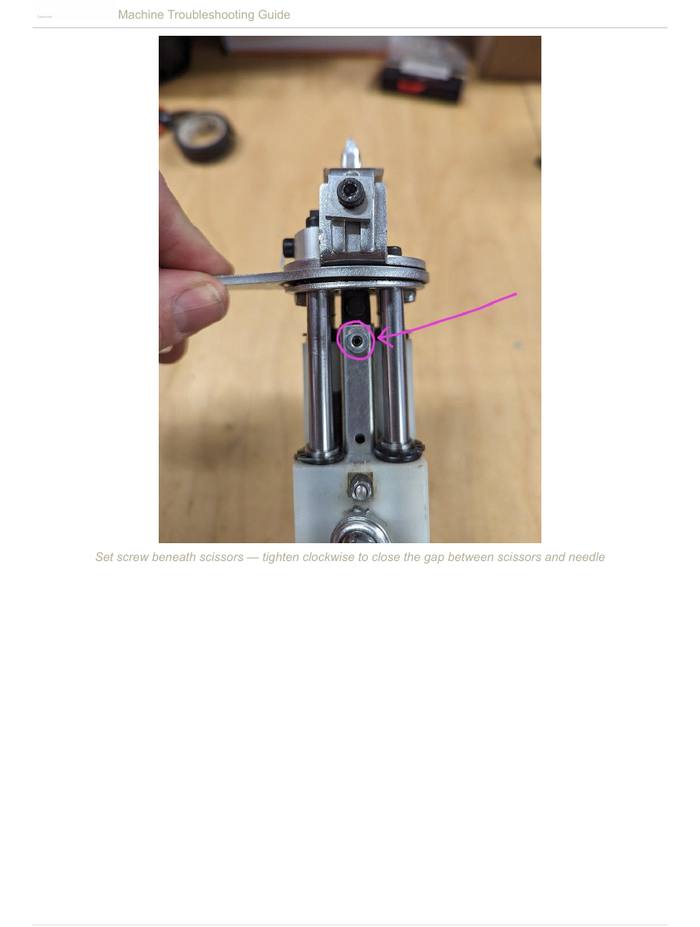 Set screw beneath scissors — tighten clockwise to close the gap between scissors and needle
